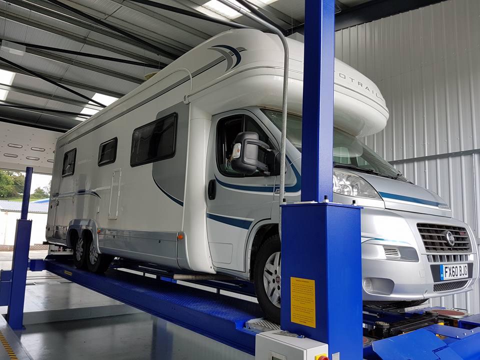 A motorhome raised on a two-post lift inside the W Sanders & Sons workshop